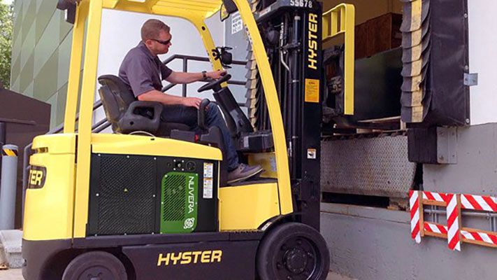 フォークリフトを運転し、荷積みドックで貨物をピックアップしている男性。